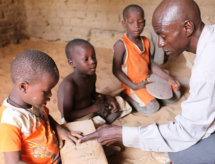 Male teacher teaching three kids